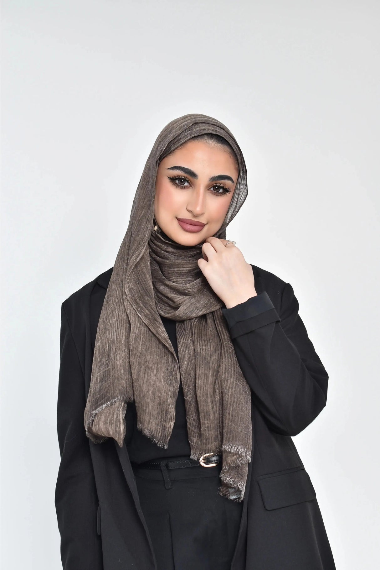 A woman wearing a brown chiffon thailendi soft hijab with a shiny finish, paired with a black outfit.